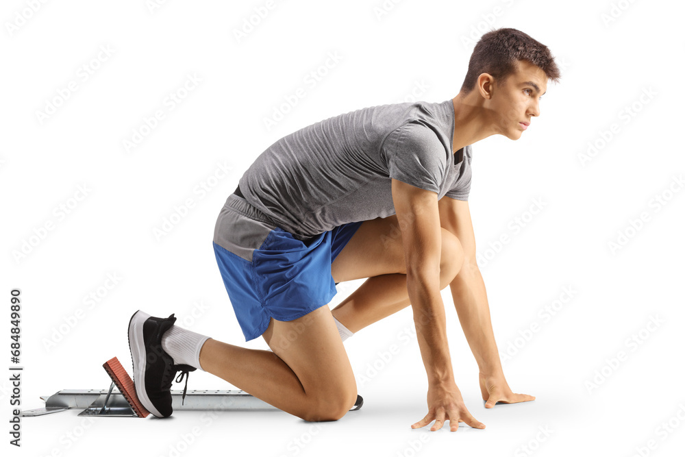 Full length profile shot of a male teenage athlete kneeling on running start blocks Full length profile shot of a male teenage athlete kneeling on running start blocks