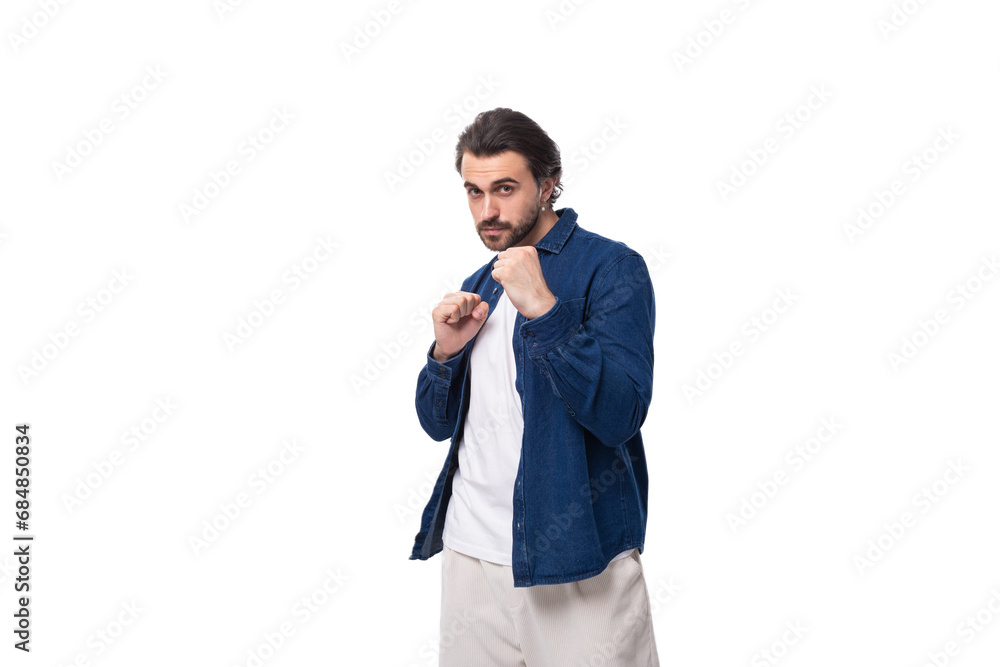 a young well-groomed brunette guy in a casual blue shirt became a boxing pose a young well-groomed brunette guy in a casual blue shirt became a boxing pose