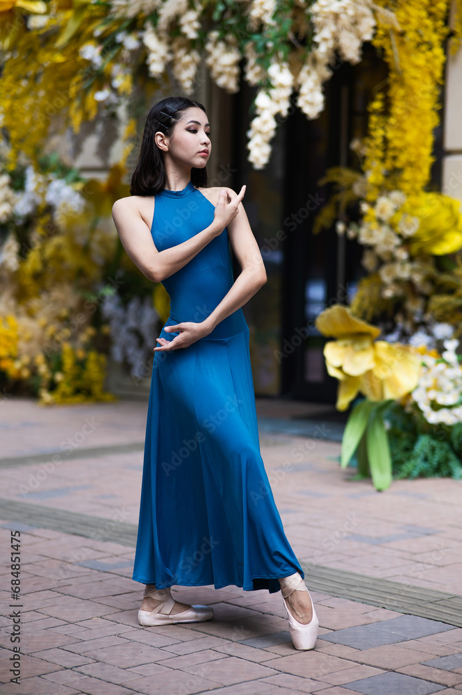 Beautiful Asian ballerina posing against the backdrop of a building decorated with flowers. Vertical photo Beautiful Asian ballerina posing against the backdrop of a building decorated with flowers. Vertical photo