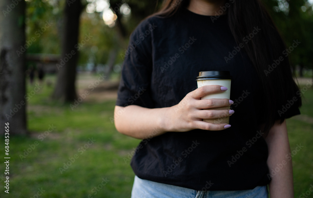 A girl enjoying a cup of coffee in the outdoor park. With space for copy. A girl enjoying a cup of coffee in the outdoor park. With space for copy.