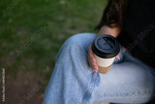 A girl sitting enjoying a cup of coffee in the outdoor park. With space for copy.