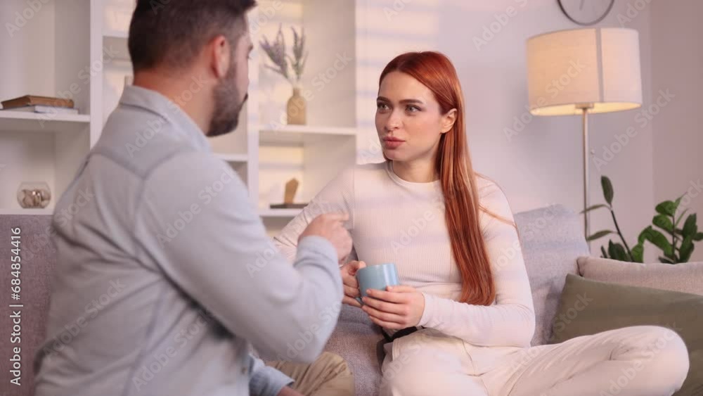 Smiling young couple talking sharing news after hard working day at cozy home Happy people enjoying spending time together sitting on couch indoors Smiling young couple talking sharing news after hard working day at cozy home Happy people enjoying spending time together sitting on couch indoors