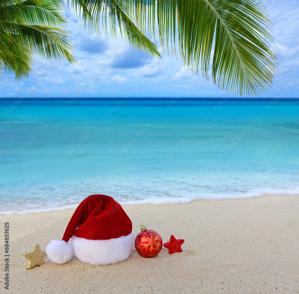 Christmas background with red Santa hat and decorations on Caribbean sand. Christmas background with red Santa hat and decorations on Caribbean sand.