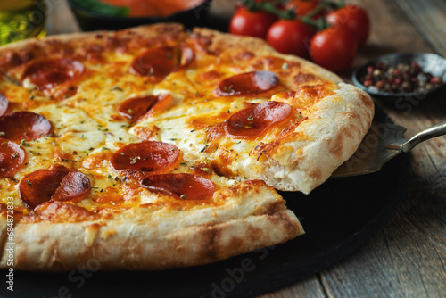 A slice of hot Italian pizza with stretching cheese. Pizza pepperoni on a dark wooden background