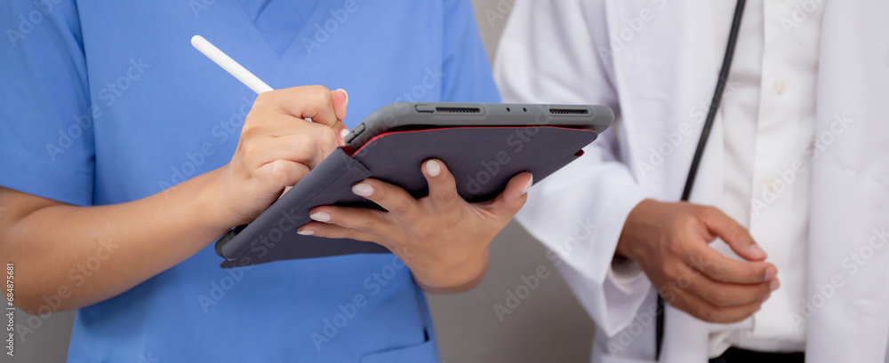 Closeup hands nurse writing report medical and health care on tablet while specialist doctor explaining and check and diagnostic with elderly patient in hospital, examining disease, senior and unwell.
