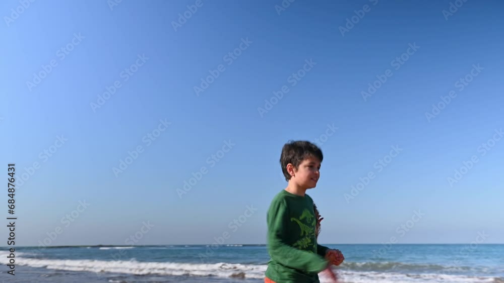 Two children, boy and girl holding hands and walking barefoot along the sandy beach on sunny day. Happy carefree childhood. Friendships. Family relationships. Lifestyle. Outdoors leisure activities Two children, boy and girl holding hands and walking barefoot along the sandy beach on sunny day. Happy carefree childhood. Friendships. Family relationships. Lifestyle. Outdoors leisure activities