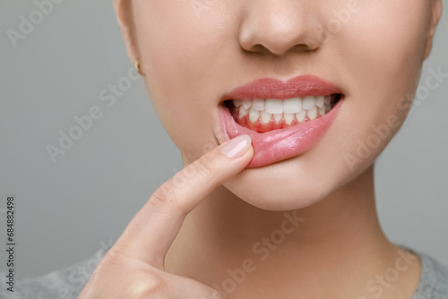 Woman showing inflamed gum on grey background, closeup photo