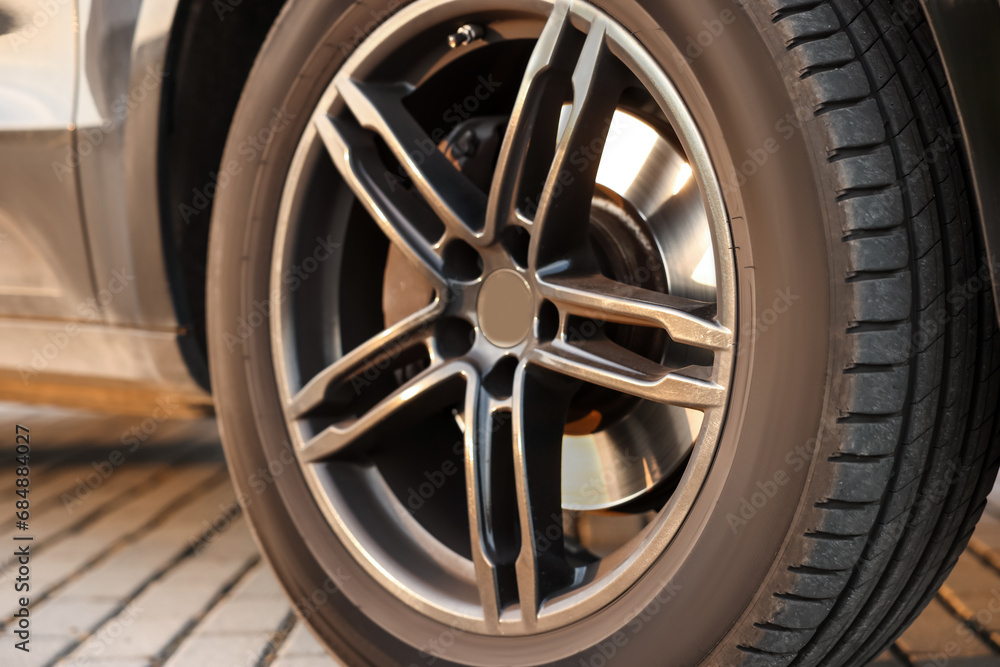 Modern car with big wheel parked on stone pavement outdoors, closeup Modern car with big wheel parked on stone pavement outdoors, closeup