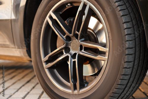 Modern car with big wheel parked on stone pavement outdoors, closeup © New Africa