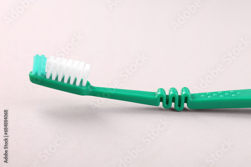 One green toothbrush on light background  closeup