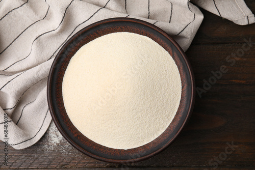 Uncooked organic semolina in bowl on wooden table, top view