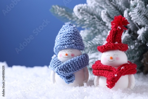 Cute decorative snowmen and fir tree on artificial snow against light blue background, closeup. Space for text © New Africa
