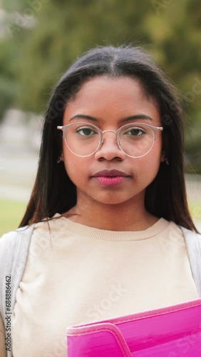 Serious hispanic teen standing outdoors at university capus looking at camera with his googles. Portrait of pretty school girl. High quality 4k footage photo