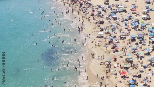 Drone flying over crowd of people sunbathing on beach of Corona Del Mar, Newport Beach, California, West coast, USA. Aerial view of Newport Bay full of tourists. People relaxing on beach at vacation 