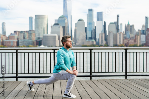 Athletic Mature Fit Man Doing Exercises in City outdoor. Happy man workout in New York city. Senior man training legs muscles doing lunges exercise. Sport, fitness and exercise.
