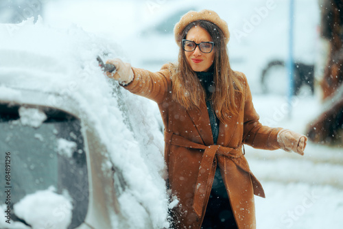 Woman with a Brush Removing snow from her Car After Blizzard. Person using a snow broom to uncover her vehicle from a trip 