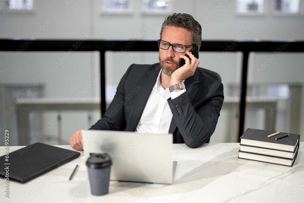 Business man talking on phone at office workplace. Employee remote working in modern office. Business man on online meeting. Hispanic business man working online. Mature business man using laptop. Business man talking on phone at office workplace. Employee remote working in modern office. Business man on online meeting. Hispanic business man working online. Mature business man using laptop.