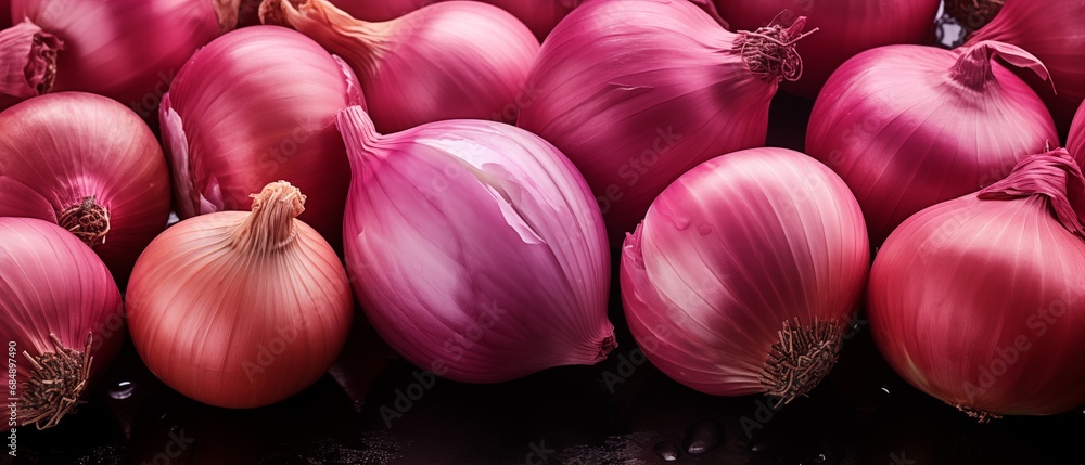 A close-up of fresh purple onions arranged on a dark surface