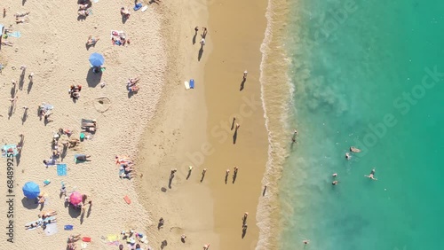 Top view of people swimming on sandy beach at Pacific Ocean, Laguna beach, Orange County, California, USA. Drone shot of tourists enjoying vacation at summer. Crystal green water of ocean, 4k footage photo