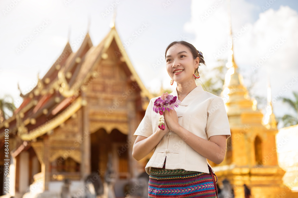 Fototapeta premium A beautiful Thai woman in a Thai-Lanna dress is putting her hands together in a prayer position.