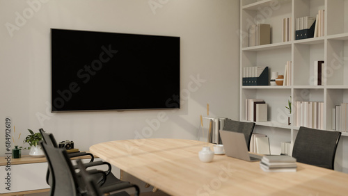 Fototapeta Naklejka Na Ścianę i Meble -  A large TV mockup screen on a white wall in a modern, minimalist meeting room. place of work