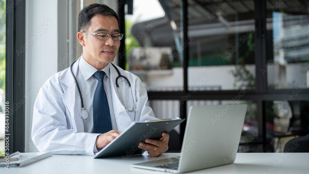 Obraz premium An experienced Asian senior male doctor is examining medical cases on report at his desk.