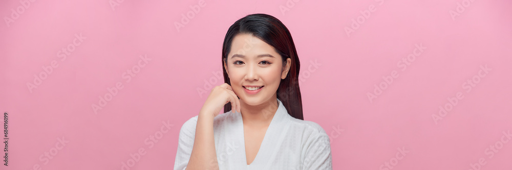 Asian woman touching her face skin concerned about anti aging skincare treatment on pink background. Asian woman touching her face skin concerned about anti aging skincare treatment on pink background.