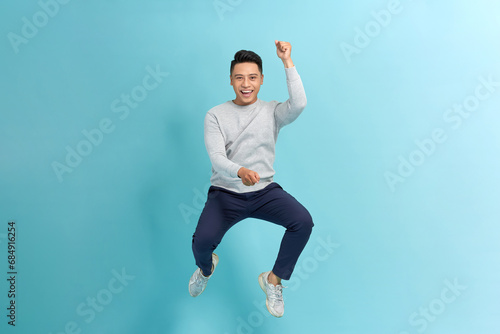 young guy jump wear shirt pants sneakers isolated on blue background