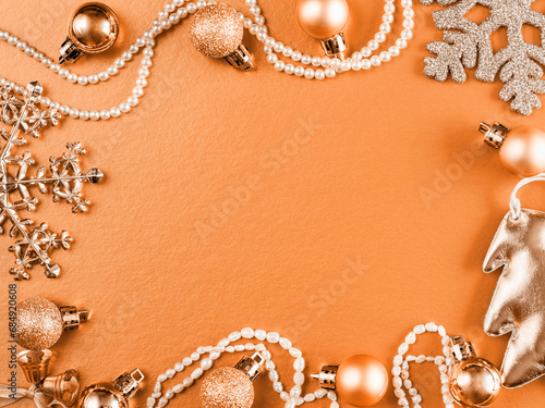 New Year and Christmas composition. Frame from orange and apricot balls, glitter snowflake, beads, chrismas tree on pastel apricot crush trend color paper background. Top view, flat lay, copy space