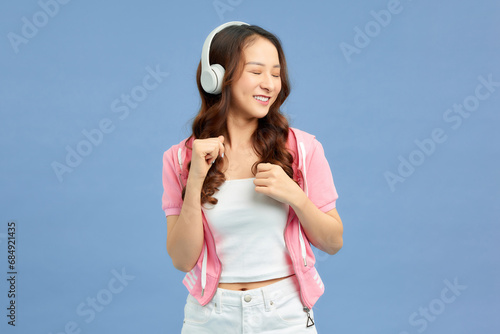 romantic woman sings along to music from headphones among blue background