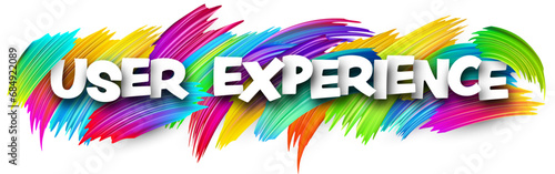 User experience paper word sign with colorful spectrum paint brush strokes over white.