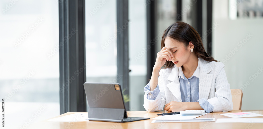 Asian women are stressed while working on laptop, Tired asian businesswoman with headache at office, feeling sick at work, copy space Asian women are stressed while working on laptop, Tired asian businesswoman with headache at office, feeling sick at work, copy space