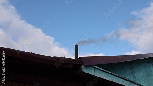 Smoke comes from the chimney of the house. The pipe on the roof. The house with a chimney