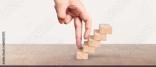 Hand liken business person stepping up  toy staircase
