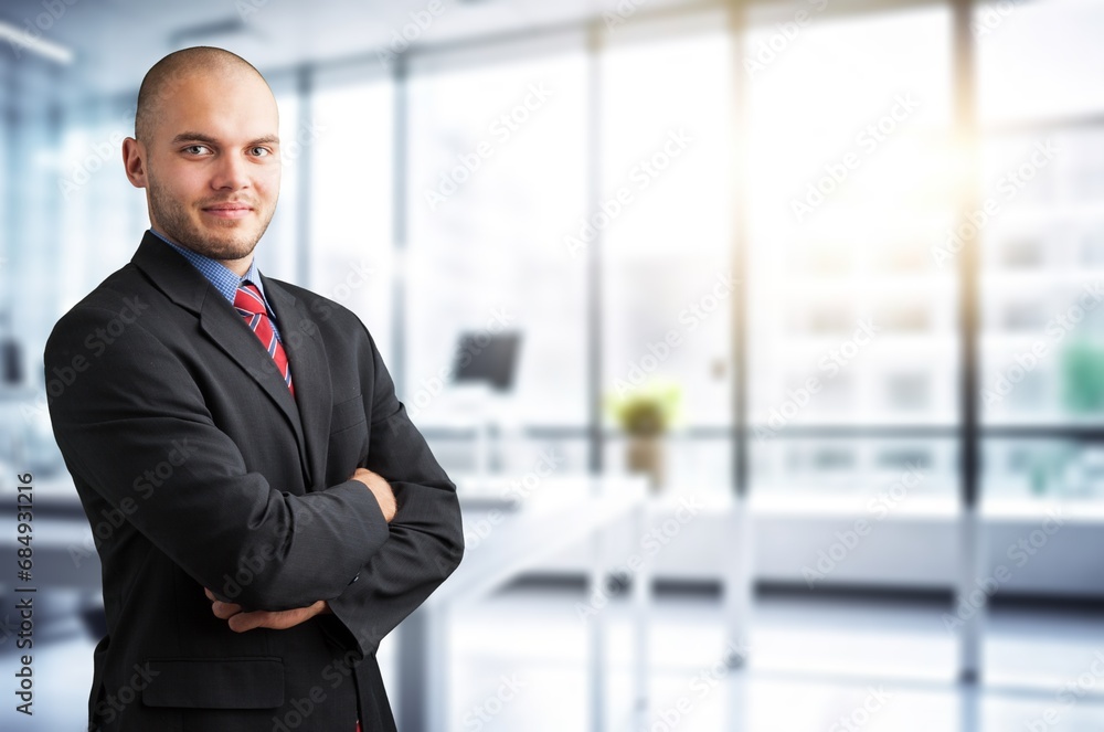 Happy businessman standing at workplace in office Happy businessman standing at workplace in office