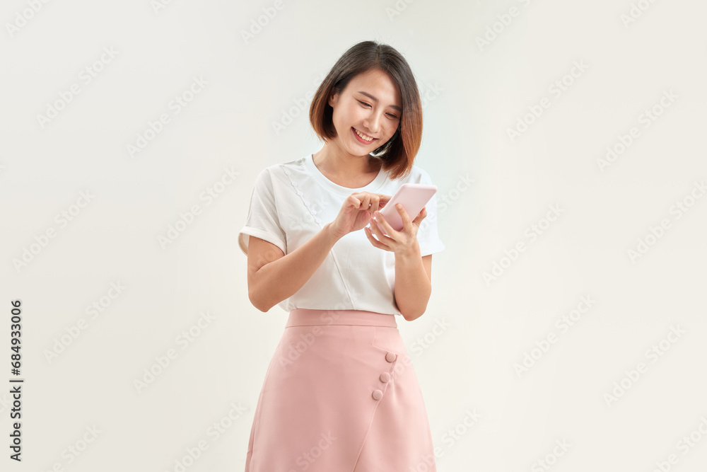 Portrait of excited asian woman using her mobile phone, isolated on white studio background Portrait of excited asian woman using her mobile phone, isolated on white studio background