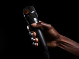 Hand holding a black microphone in a music studio, capturing the essence of sound, entertainment, and communication