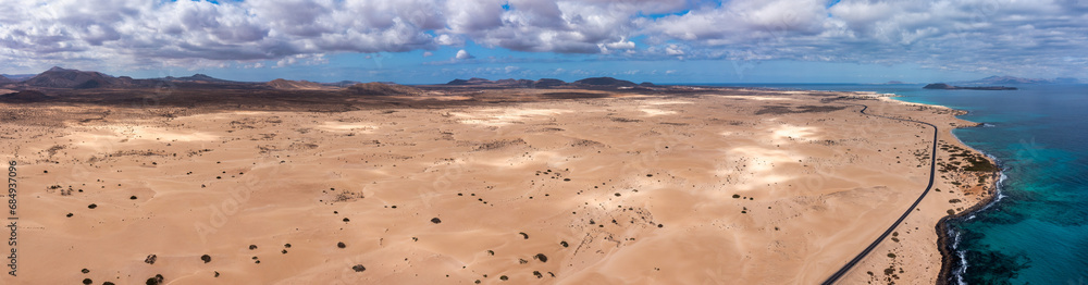 Panoramic high angle aerial drone view of Corralejo National Park (Parque Natural de Corralejo) with sand dunes located in the northeast corner of the island of Fuerteventura, Canary Islands, Spain. Panoramic high angle aerial drone view of Corralejo National Park (Parque Natural de Corralejo) with sand dunes located in the northeast corner of the island of Fuerteventura, Canary Islands, Spain.