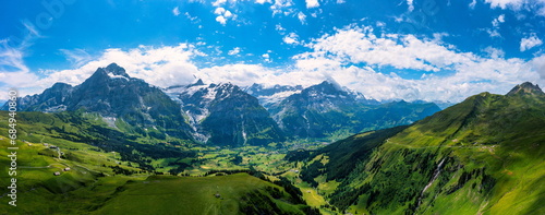 Grindelwald view and summer Swiss Alps mountains panorama landscape, green fields and high peaks in background, Switzerland, Bernese Oberland, Europe.
