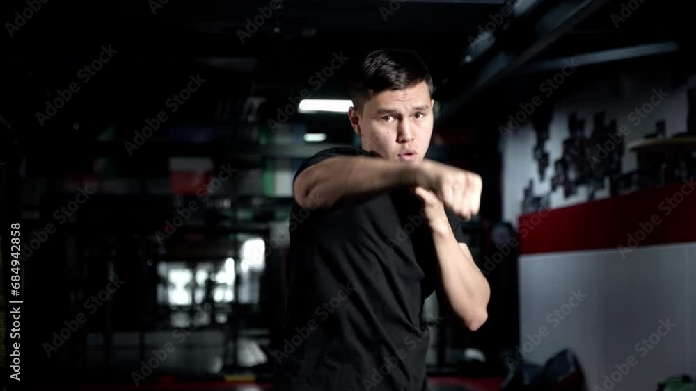 A fierce athlete in a sleek black shirt shows off his toned muscles and intense determination as he throws a powerful punch in an indoor boxing match A fierce athlete in a sleek black shirt shows off his toned muscles and intense determination as he throws a powerful punch in an indoor boxing match