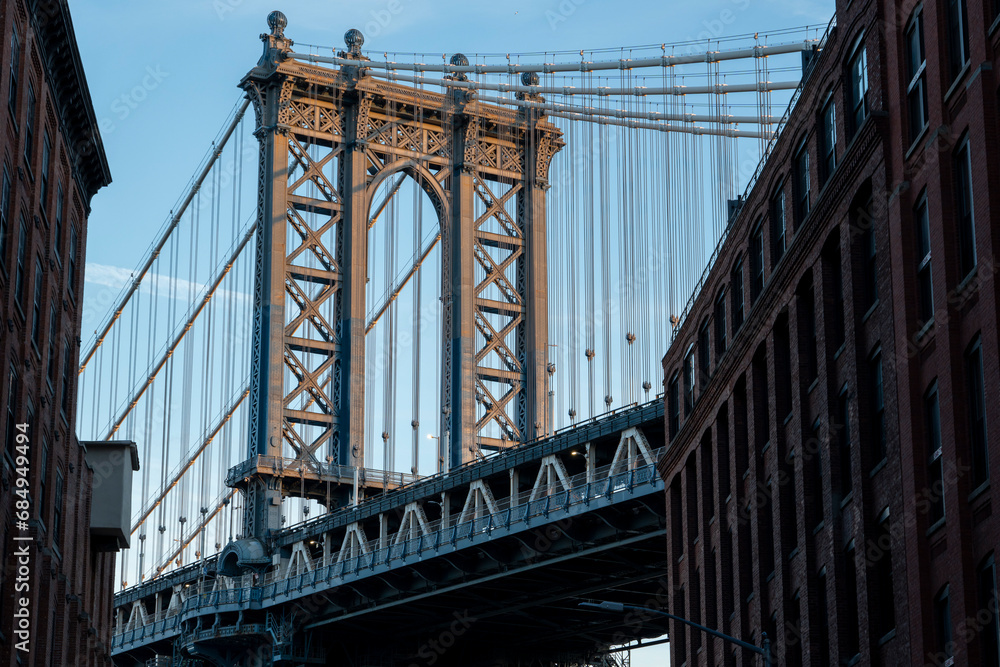 Obraz premium Manhattan Bridge between Manhattan and Brooklyn over East River seen from a narrow alley enclosed by two brick buildings on a sunny morning in Washington street in Dumbo, Brooklyn, NYC