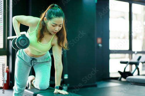 Active Asian sportswoman doing a weight training workout in indoor gym.