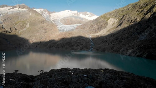 Aerial view of Gauli glacier in the Bernese Oberland region of the Swiss Alps with a view of the glacial lake in the shadows of sunrise. photo