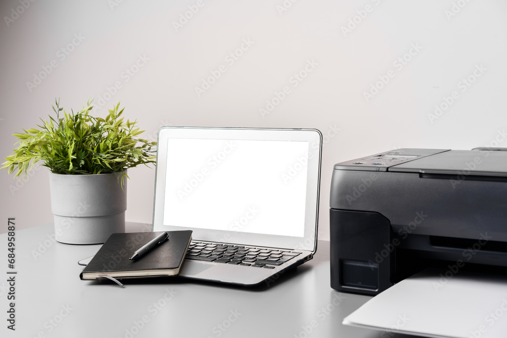 Printer and laptop on grey table in office Printer and laptop on grey table in office