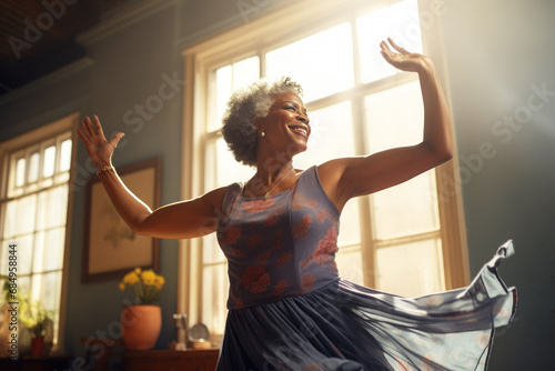 Smiling afro american elderly woman dancing near the window