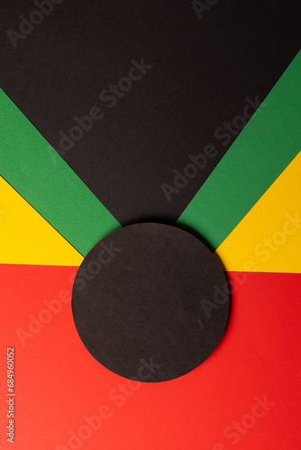 Vertical image of green, yellow and red papers with black circle and copy space on black background