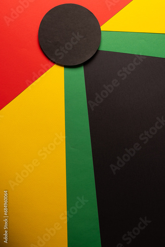 Vertical image of green, yellow and red papers with black circle and copy space on black background
