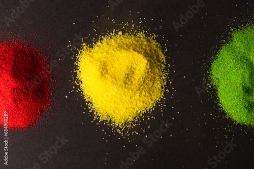 Green, yellow and red powders with copy space on black background