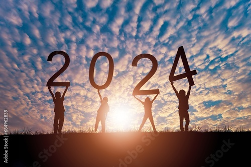 Silhouette friends holding 2024 number on sunset sky