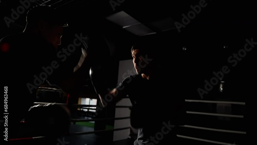 A shadowy figure unleashes their pent-up rage upon the darkness of a boxing ring, captured in a striking video. photo